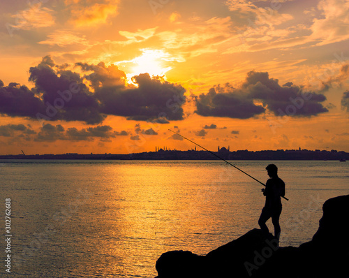 Fototapeta Naklejka Na Ścianę i Meble -  silhouette of fisherman at sunset