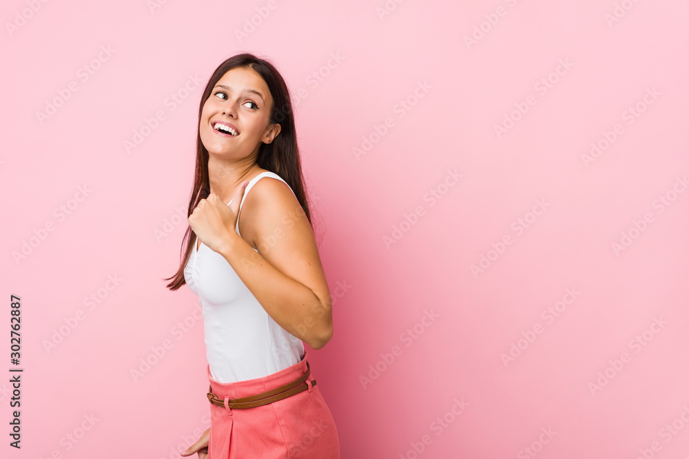 Young cute woman points with thumb finger away, laughing and carefree. Young cute woman points with thumb finger away, laughing and carefree.