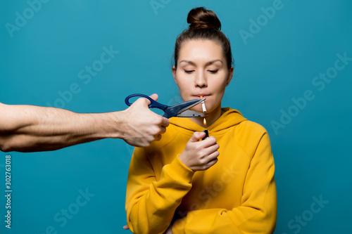Foto a girl in bright clothes is going to light a cigarette, but a male hand with sci