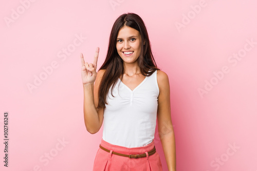 Young cute woman showing a horns gesture as a revolution concept.