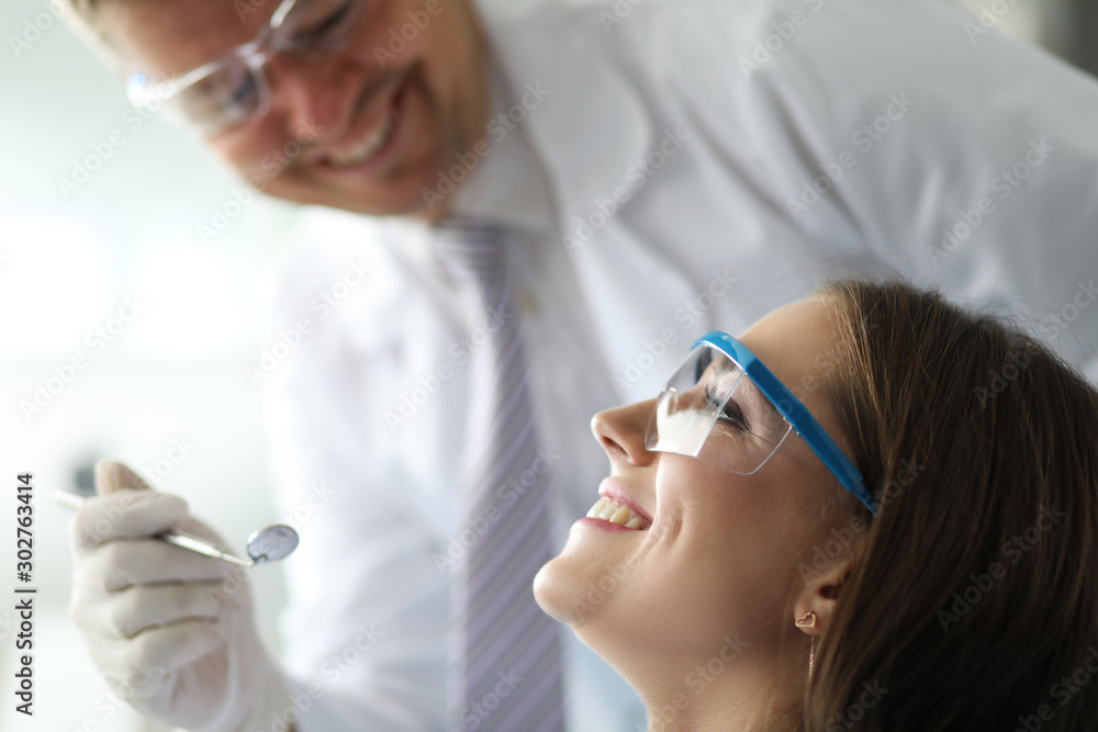 Male dentist working with happy and smiling female visitor Male dentist working with happy and smiling female visitor