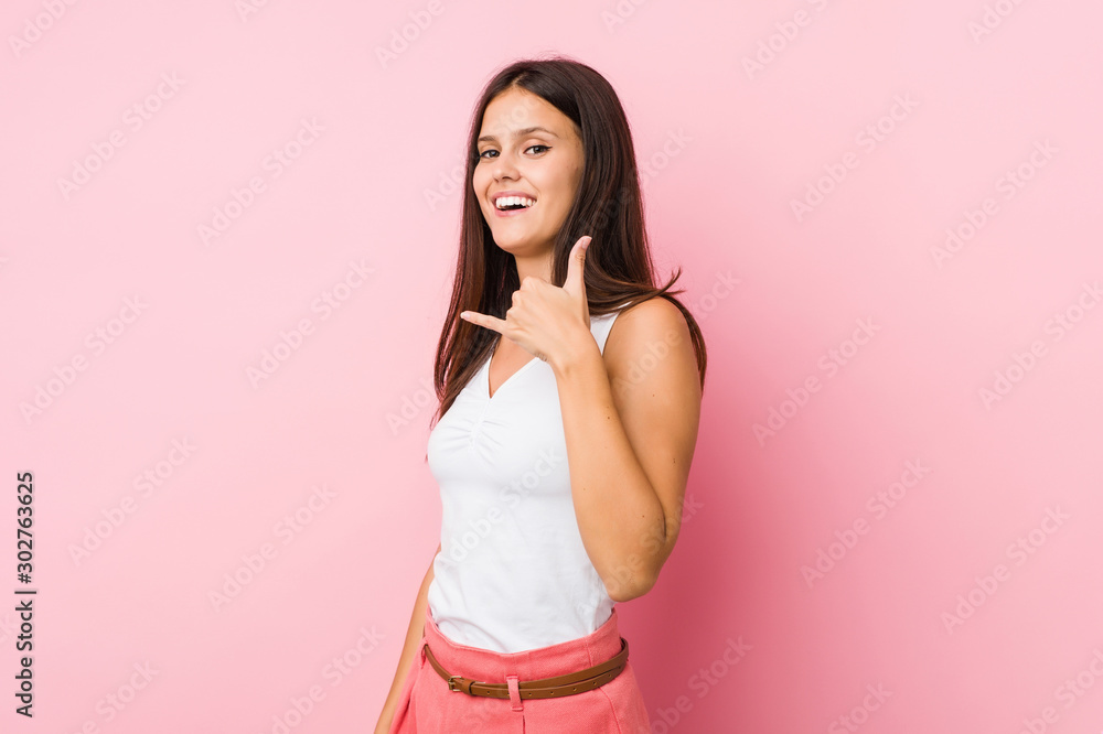 Young cute woman showing a mobile phone call gesture with fingers. Young cute woman showing a mobile phone call gesture with fingers.