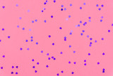 Photo of purple hearts glitter sprinkles on pink trendy background. Festive holiday background for your projects. Celebration concept. Love pattern. Top view, flat lay