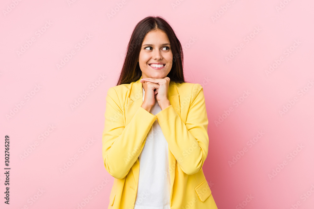 Young business woman keeps hands under chin, is looking happily aside. Young business woman keeps hands under chin, is looking happily aside.