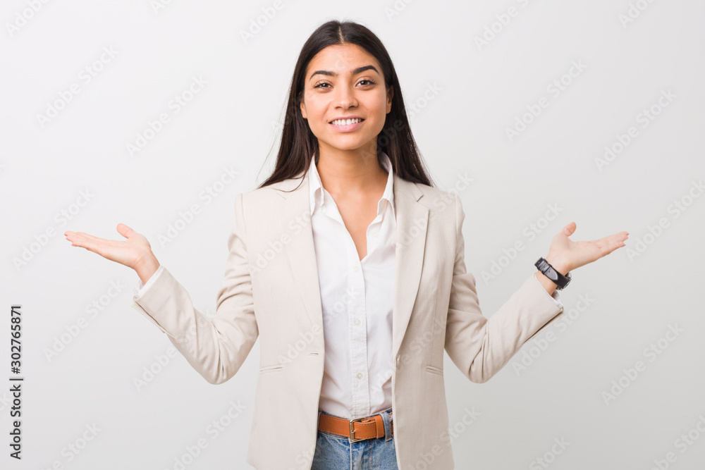Young business arab woman isolated against a white background makes scale with arms, feels happy and confident. Young business arab woman isolated against a white background makes scale with arms, feels happy and confident.