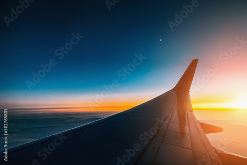 Sunset from airplane window view. Aircraft wing from illuminator view.