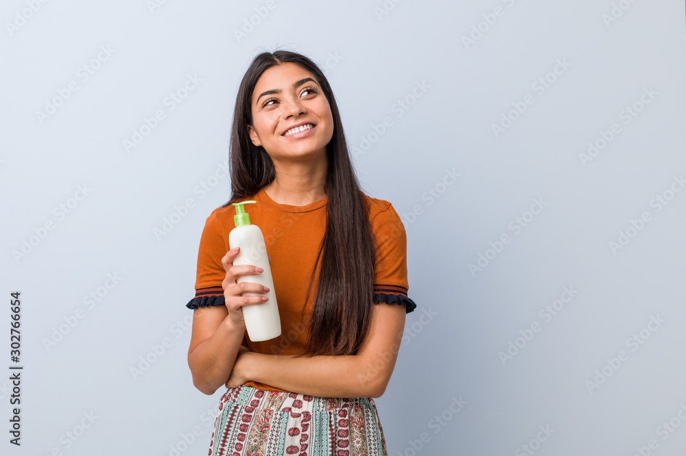 Young arab woman holding a cream bottle smiling confident with crossed arms. Young arab woman holding a cream bottle smiling confident with crossed arms.