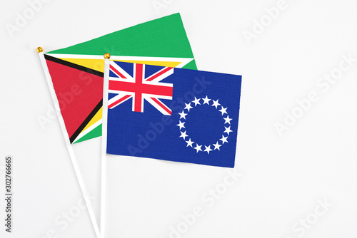 Cook Islands and Guyana stick flags on white background. High quality fabric, miniature national flag. Peaceful global concept.White floor for copy space.