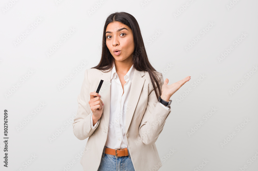Young arab woman holding a credit card impressed holding copy space on palm. Young arab woman holding a credit card impressed holding copy space on palm.