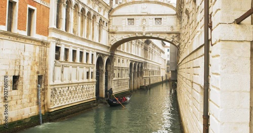 Gondolier on a gondola with a paddle carries tourists along the back canal. Historic Venice Italy. Dynamic shot filmed in 4k 2160p photo