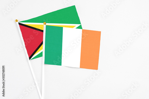 Ireland and Guyana stick flags on white background. High quality fabric, miniature national flag. Peaceful global concept.White floor for copy space.