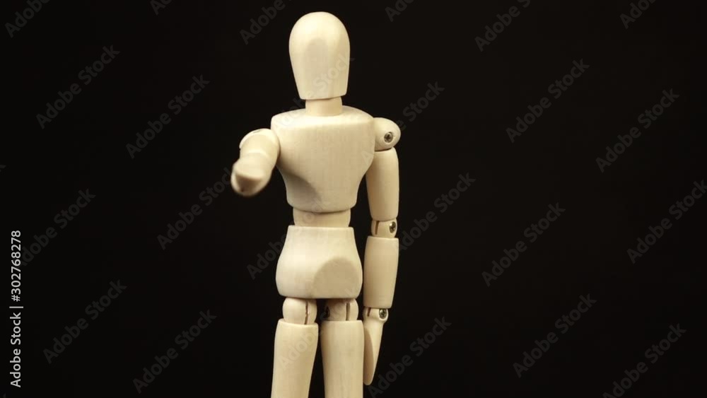 the wooden doll pulls its arm forward and rotates 360 degrees on a black background the wooden doll pulls its arm forward and rotates 360 degrees on a black background