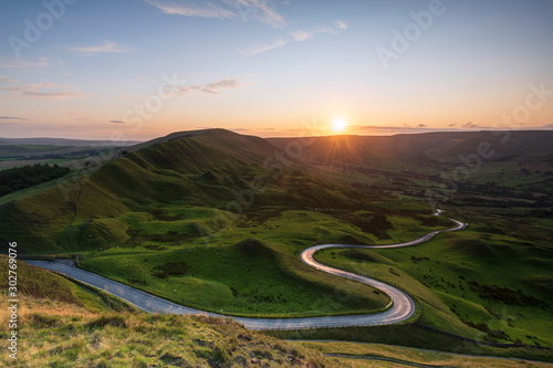 Long and winding rural road leading through green hills in the Peak District, with Rushup Edge, Peak District National Park, Derbyshire photo