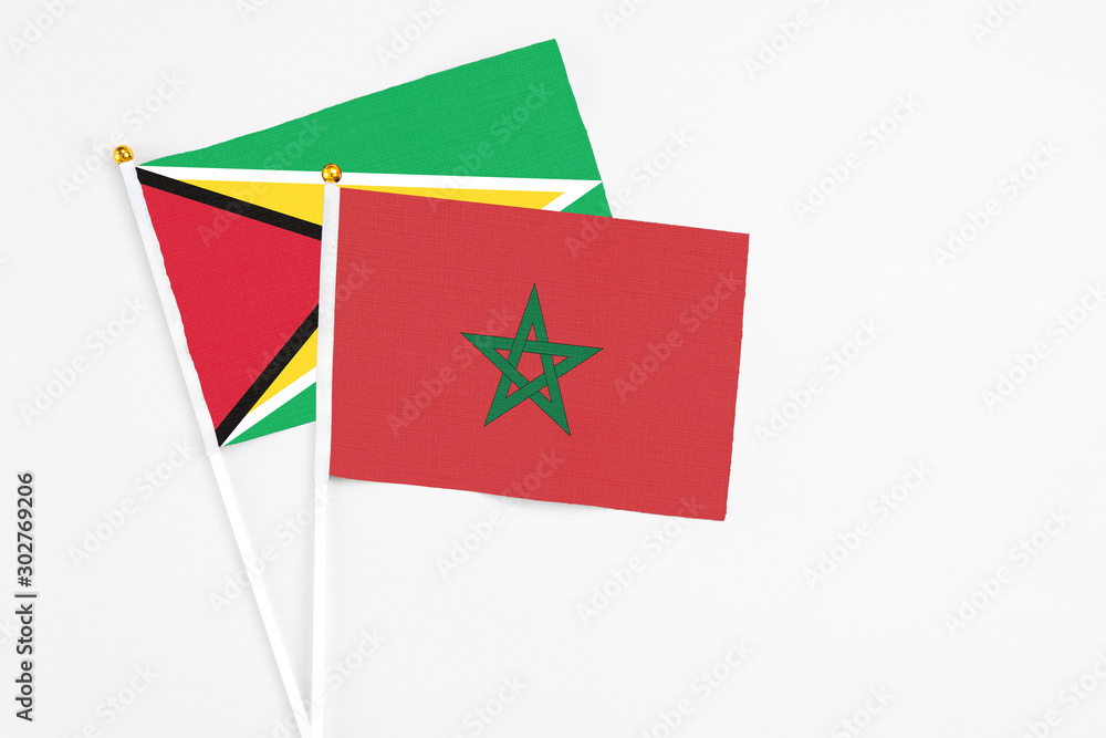 Morocco and Guyana stick flags on white background. High quality fabric, miniature national flag. Peaceful global concept.White floor for copy space. Morocco and Guyana stick flags on white background. High quality fabric, miniature national flag. Peaceful global concept.White floor for copy space.