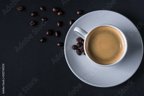 Top view of coffee cup on pile of coffee beans and cloth on wood dark background with copy space for write text concept