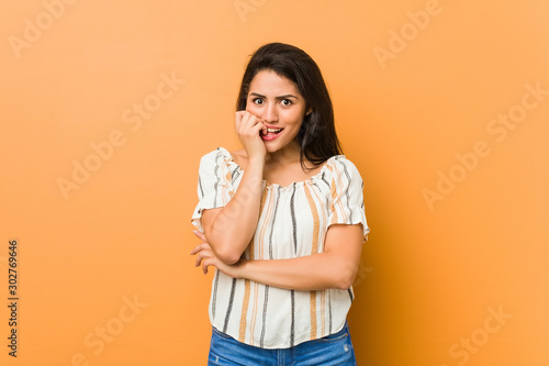 Young curvy woman biting fingernails, nervous and very anxious.