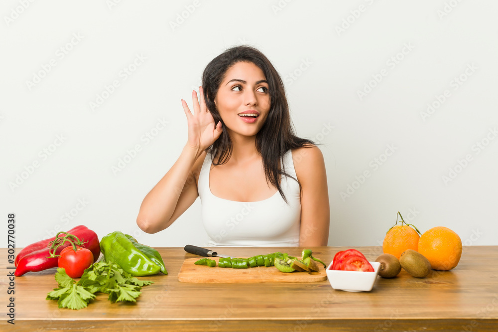 Young curvy woman preparing a healthy meal trying to listening a gossip. Young curvy woman preparing a healthy meal trying to listening a gossip.