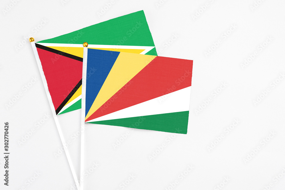 Seychelles and Guyana stick flags on white background. High quality fabric, miniature national flag. Peaceful global concept.White floor for copy space.