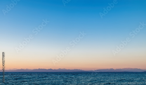 Idyllic sunset on the shore of north west coast of Lefkada island, Greece. Simple seascape with water surface and sunset sky