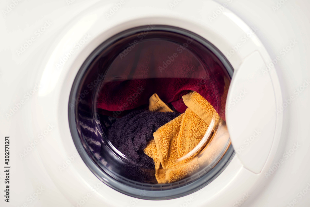 White washing machine door full of clothes, close up. Laundry concept White washing machine door full of clothes, close up. Laundry concept