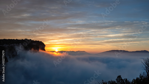 Sunrise with blue sky above the clouds in the mountains. View from high point. Very early morning with fog and colorful clouds.