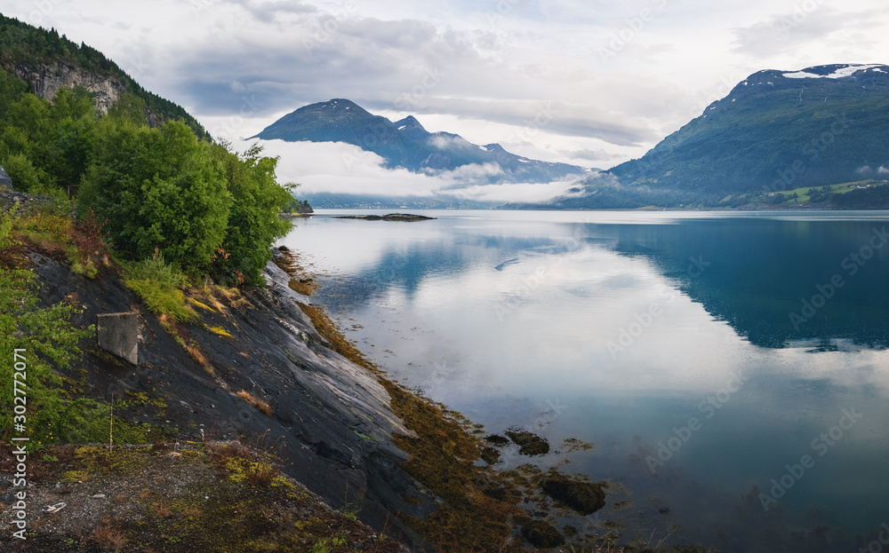 Nordfjord is a bay near Stryn village and district in Sogn og Fjordane, Norway, Norway. Scandinavian nature fjord and mountain in National Park in summer. Summer view of scenic fog over the mountains