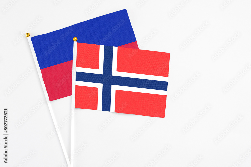 Obraz premium Bouvet Islands and Haiti stick flags on white background. High quality fabric, miniature national flag. Peaceful global concept.White floor for copy space.