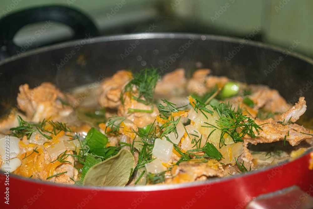 Meat with onions, carrots, dill and Bay leaf is stewed in a saucepan. Home cooking. Close up.