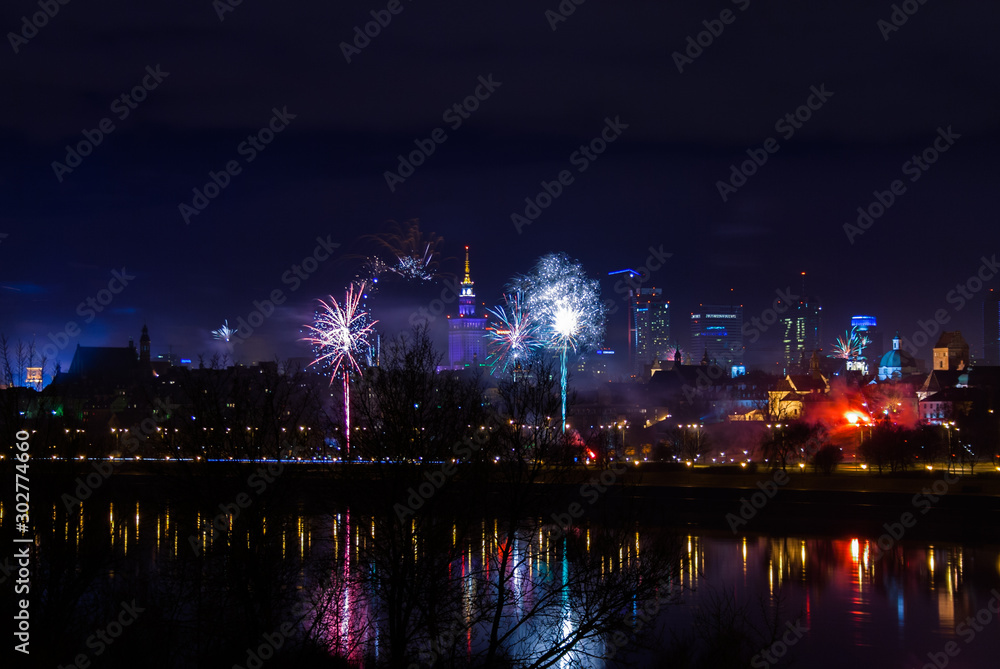 New Year's fireworks show in Warsaw, Poland at night, view from the Vistula River and city center