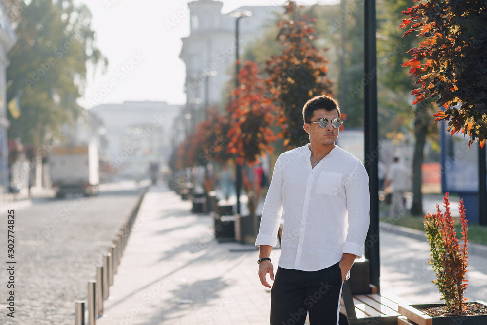Obraz premium young stylish guy in a shirt walking down a European street on a sunny day