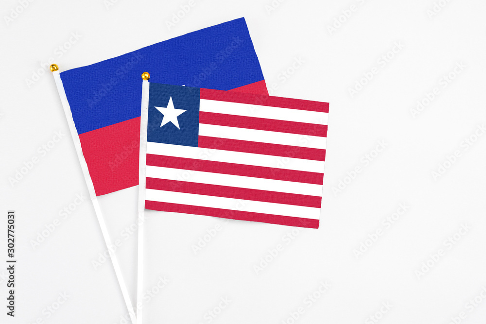 Liberia and Haiti stick flags on white background. High quality fabric, miniature national flag. Peaceful global concept.White floor for copy space. Liberia and Haiti stick flags on white background. High quality fabric, miniature national flag. Peaceful global concept.White floor for copy space.