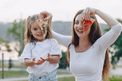 mom and daughter playing with pizza in nature