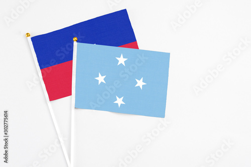 Micronesia and Haiti stick flags on white background. High quality fabric, miniature national flag. Peaceful global concept.White floor for copy space. © sezerozger