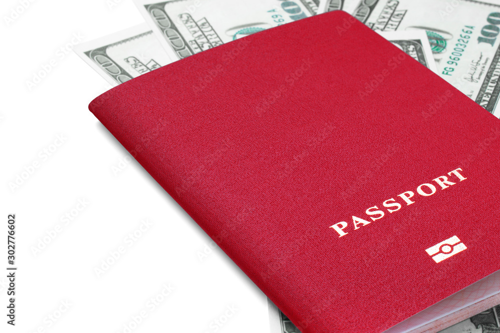 Closeup side view of red passport for international travel on scattered one hundred dollar bills with copy space isolated on white background. Vacations, business, travel, currency exchange concept Closeup side view of red passport for international travel on scattered one hundred dollar bills with copy space isolated on white background. Vacations, business, travel, currency exchange concept