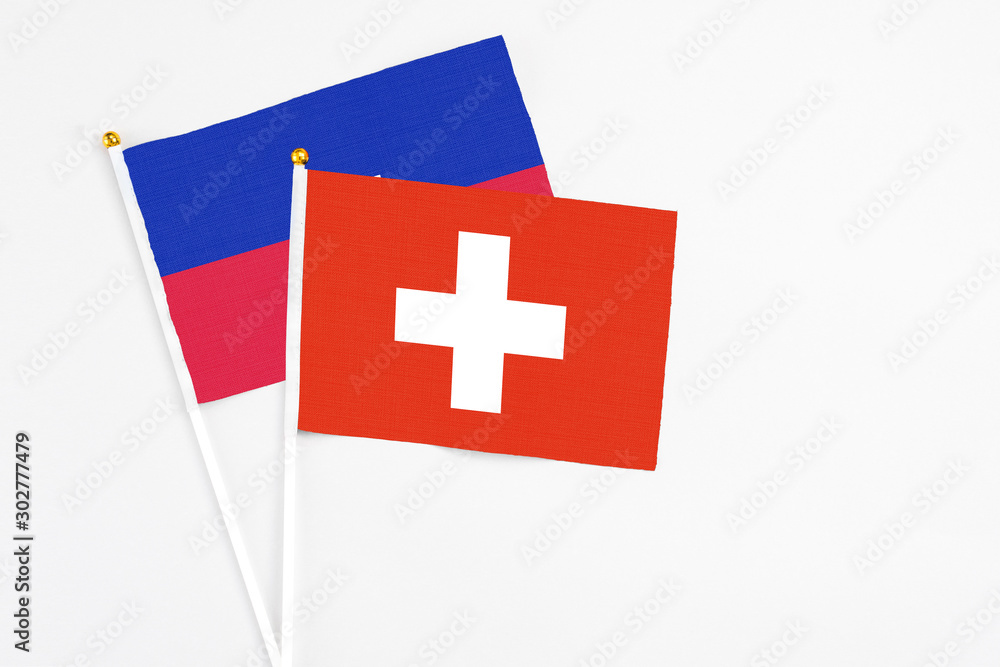 Switzerland and Haiti stick flags on white background. High quality fabric, miniature national flag. Peaceful global concept.White floor for copy space.