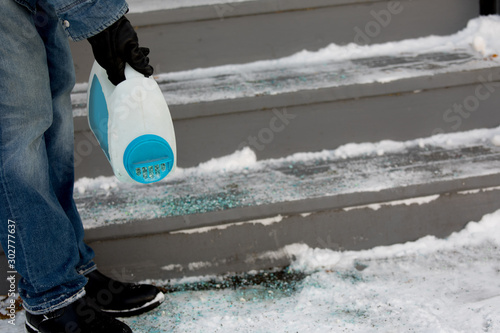 winter safety -  a worker putting ice melter on an icy  stairway photo