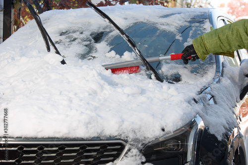 winter safety - a person cleaning the snow from the windshield of a car photo