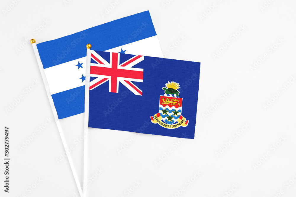 Fototapeta premium Cayman Islands and Honduras stick flags on white background. High quality fabric, miniature national flag. Peaceful global concept.White floor for copy space.