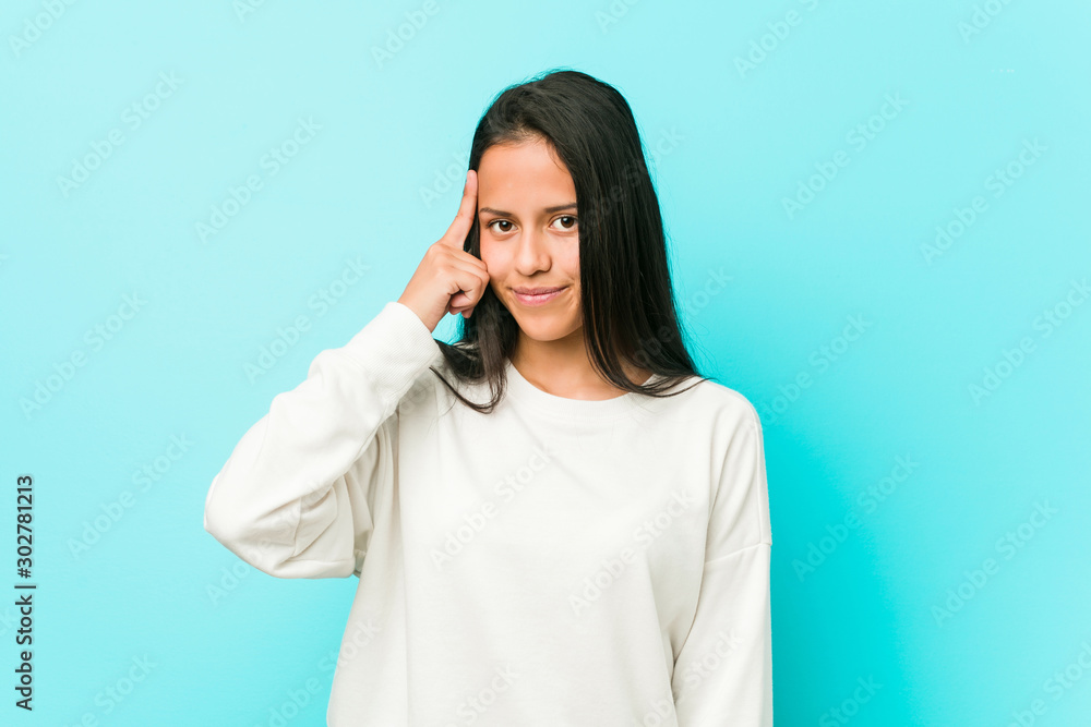 Young pretty hispanic woman pointing temple with finger, thinking, focused on a task. Young pretty hispanic woman pointing temple with finger, thinking, focused on a task.