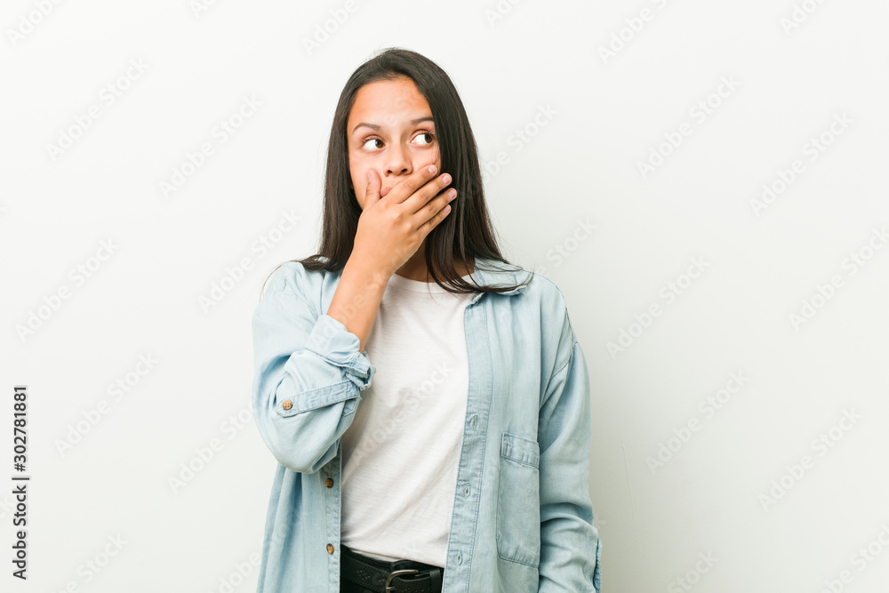 Young hispanic woman thoughtful looking to a copy space covering mouth with hand. Young hispanic woman thoughtful looking to a copy space covering mouth with hand.