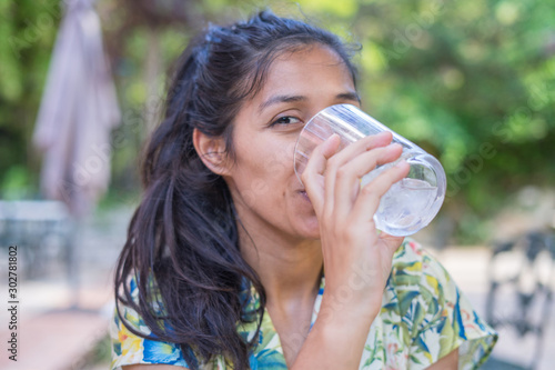 Young indian woman drinking water in the park