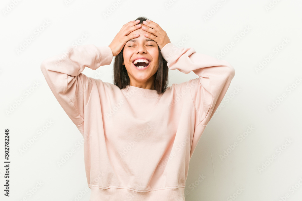 Young cute hispanic teenager woman laughs joyfully keeping hands on head. Happiness concept. Young cute hispanic teenager woman laughs joyfully keeping hands on head. Happiness concept.
