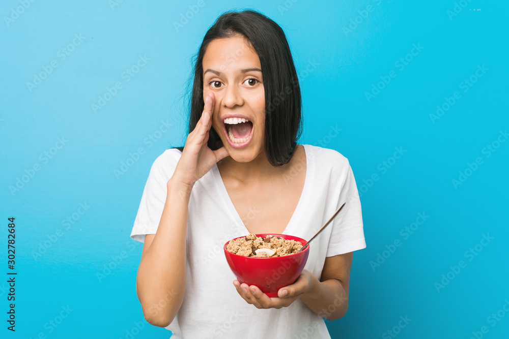 Young hispanic woman holding a cereal bowl shouting excited to front. Young hispanic woman holding a cereal bowl shouting excited to front.