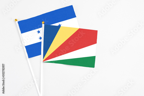 Seychelles and Honduras stick flags on white background. High quality fabric  miniature national flag. Peaceful global concept.White floor for copy space.