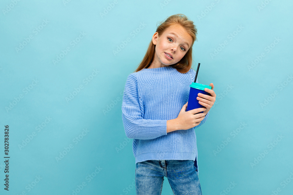 Copyspace photo of girl in a blue sweater against a blue wall with a glass of cocoa Copyspace photo of girl in a blue sweater against a blue wall with a glass of cocoa