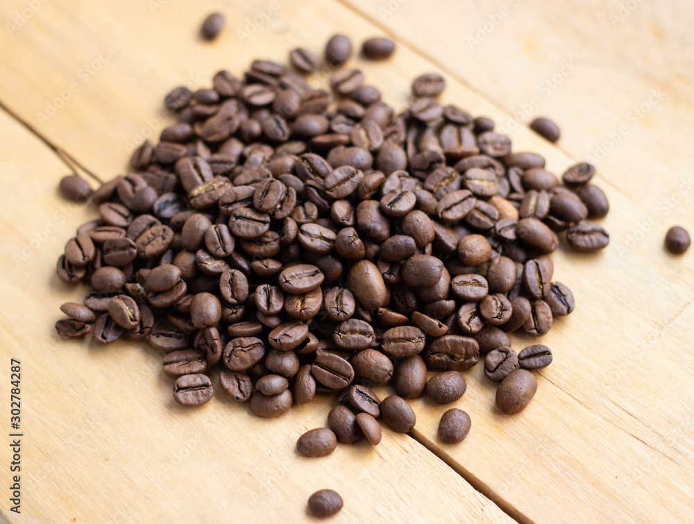 Black coffee grains lie on a brown wooden table, background Black coffee grains lie on a brown wooden table, background