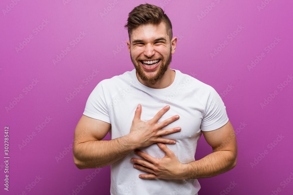 Young handsome caucasian man laughs happily and has fun keeping hands on stomach. Young handsome caucasian man laughs happily and has fun keeping hands on stomach.