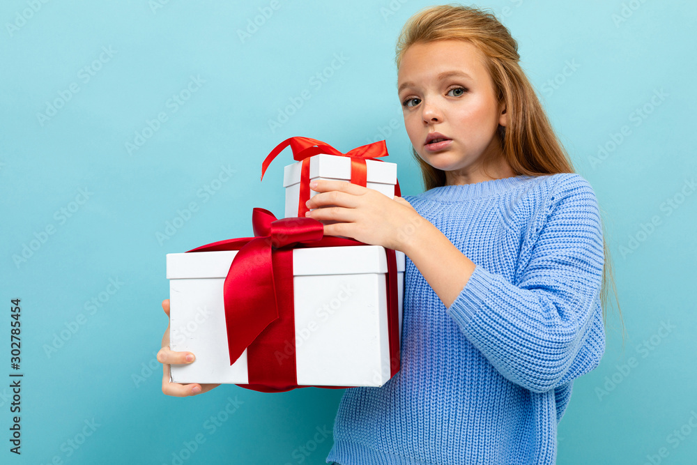 surprised cute schoolgirl on a blue background with a slide of gift boxes surprised cute schoolgirl on a blue background with a slide of gift boxes