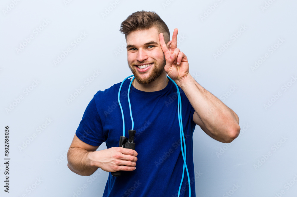 Young caucasian sportsman with a jump rope showing victory sign and smiling broadly. Young caucasian sportsman with a jump rope showing victory sign and smiling broadly.