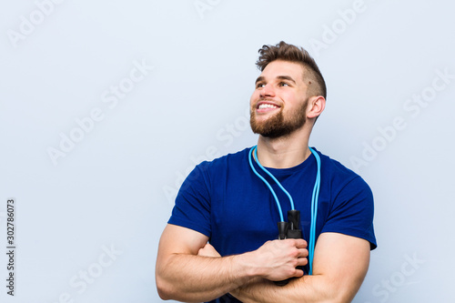 Young caucasian sportsman with a jump rope smiling confident with crossed arms.